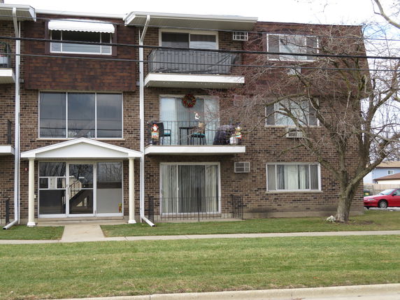 Front view of a multi-story brick apartment building with balconies.