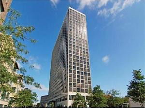 Front view of a tall, modern skyscraper with a grid-like facade and many windows.