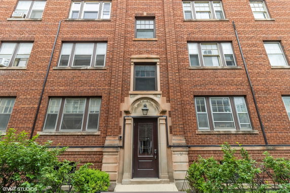 Front view of a multi-story brick apartment building with several windows and a central entrance.