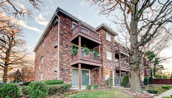 Front view of a multi-story brick apartment building with balconies.