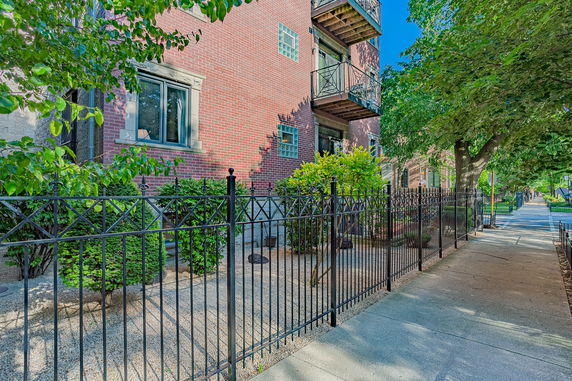 Front view of a brick apartment building with balconies and metal fencing.
