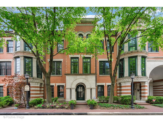 Front view of a multi-story brick building with arched windows and entrance.