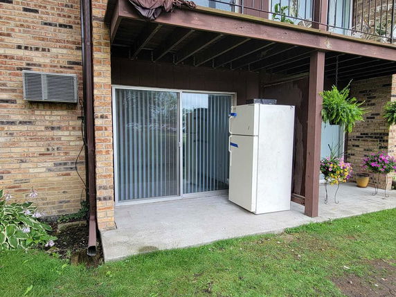 Rear view of a brick building with a covered patio and sliding glass doors.