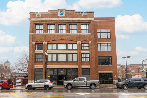 Front view of a brick multi-story building with large windows.