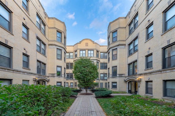 Front view of an apartment building with a courtyard and multiple windows.