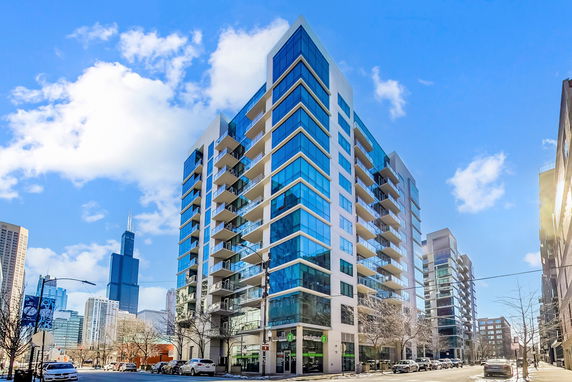 Front view of a modern multi-story apartment building with large glass windows and balconies.