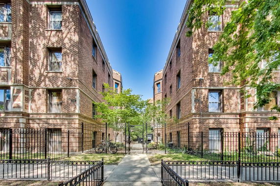 Front view of brick apartment buildings with a gated entrance.
