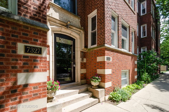 Front view of a brick building with numbered entrance and steps.