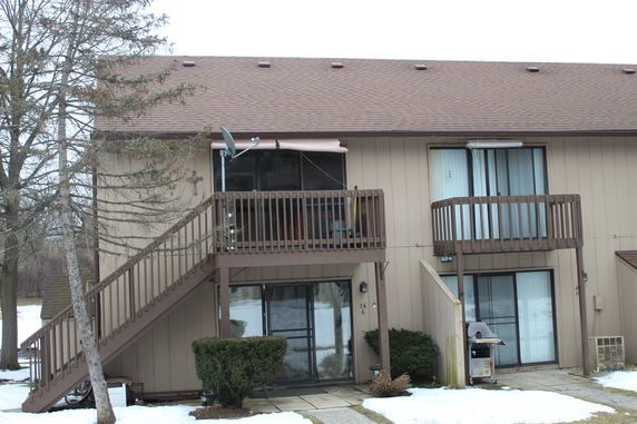 Front view of a two-story house with balconies and external staircase.