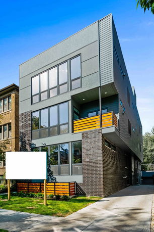 Front view of a modern three-story house with large windows and a driveway.