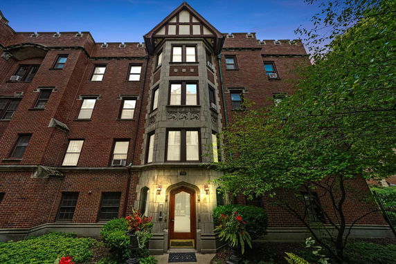 Front view of a brick apartment building with decorative details and a central entrance.