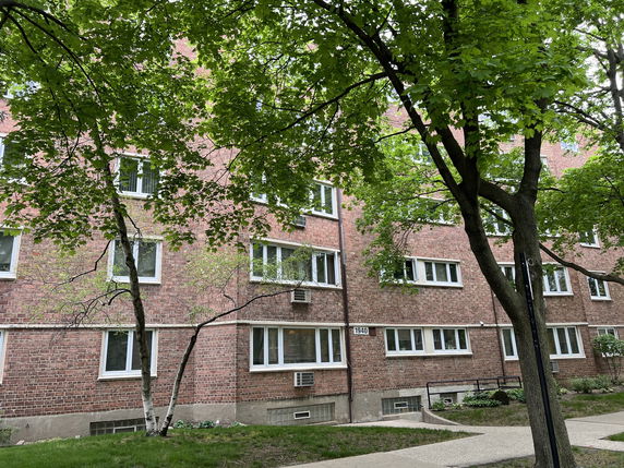Front view of a multi-story brick residential building with several windows.