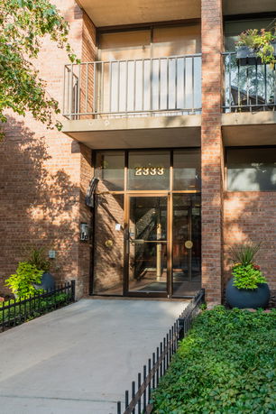 Front view of a building entrance with brick exterior and balcony.