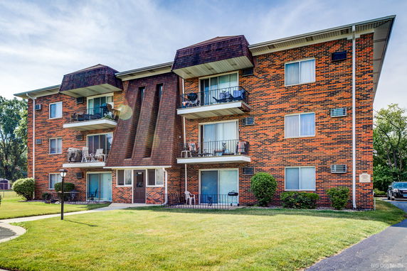 Front view of a multi-story apartment building with balconies and a brick exterior.
