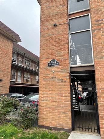 Front view of a multi-story brick apartment building with visible balconies.