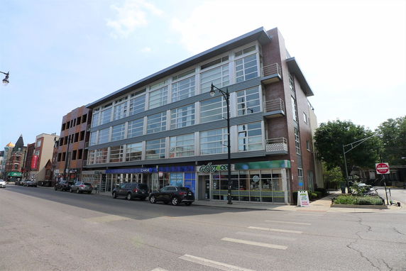Front view of a multi-story commercial building with large windows and retail shops on the ground floor.