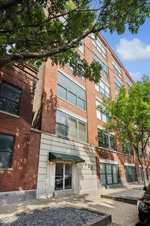 Front view of a multi-story brick building with large windows.