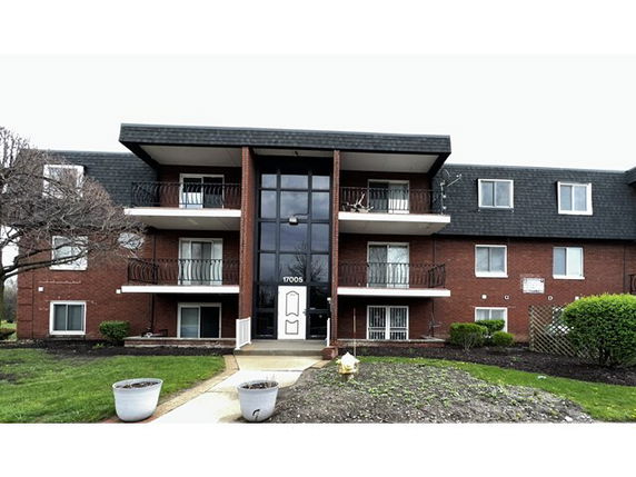 Front view of a multi-story brick apartment building with balconies.