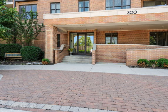 Front view of a multi-story brick building entrance with steps and glass doors.