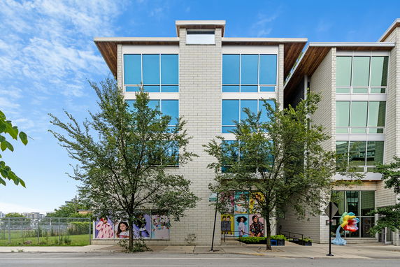 Front view of a modern multi-story building with large windows and decorative murals.