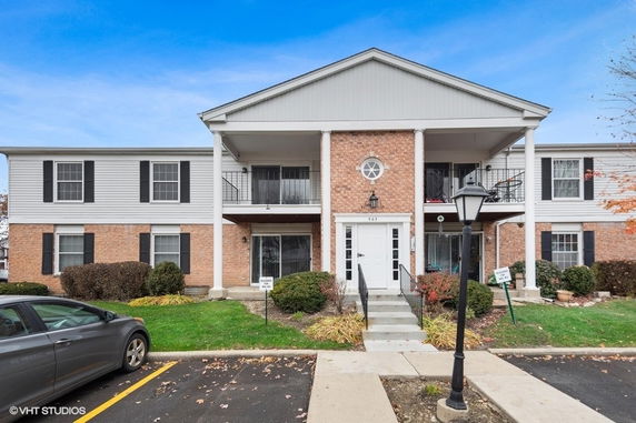 Front view of a two-story brick and siding apartment building with balconies.