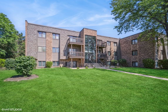 Front view of a three-story apartment building with balconies and large windows.