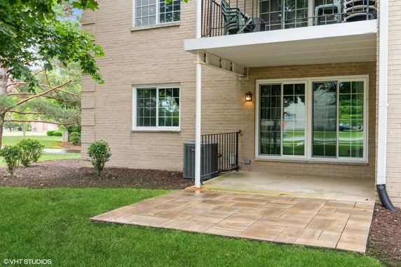 Exterior view of a two-story brick building with a balcony above a patio area.