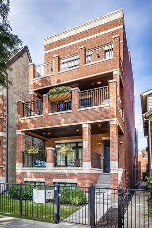 Front view of a multi-story brick house with balconies and a gated entrance.
