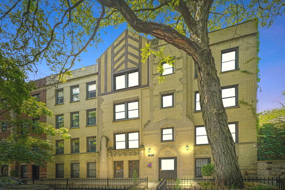 Front view of a multi-story residential building with decorative brickwork and symmetrical window placement.