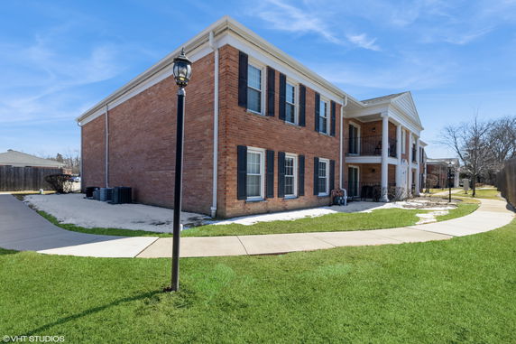 Front view of a two-story brick building with multiple windows and a small porch.