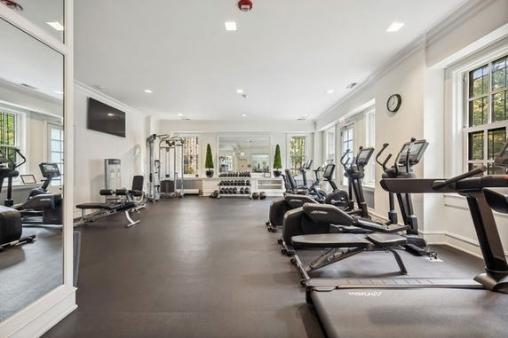 Indoor gym with exercise equipment and large mirrors.