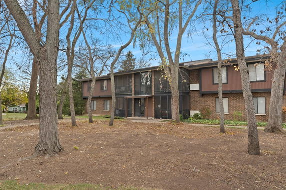 Front view of a two-story building with a brick facade and large trees in the foreground.