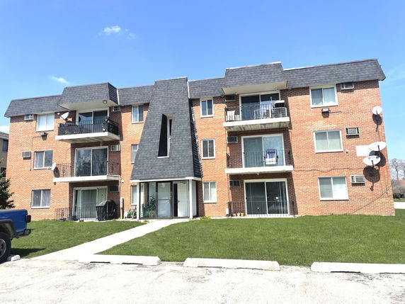 Front view of a three-story apartment building with balconies.