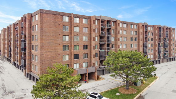 Front view of a large brick apartment building with multiple balconies and windows.
