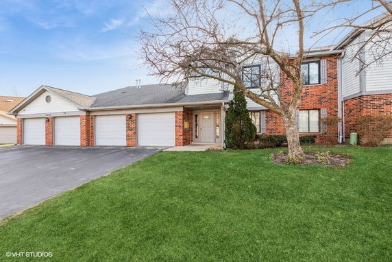 Front view of a two-story brick house with attached garage and a driveway.