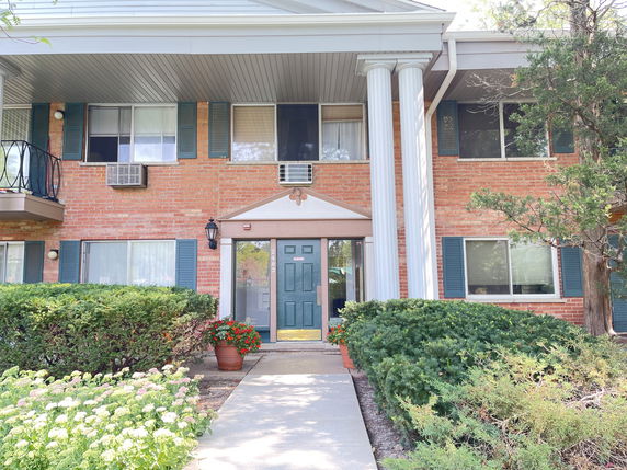 Front view of a two-story building with brick facade and large columns at the entrance.