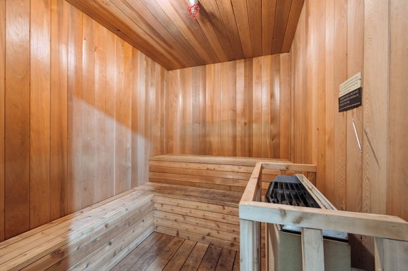 Wooden sauna room with benches and a heater.