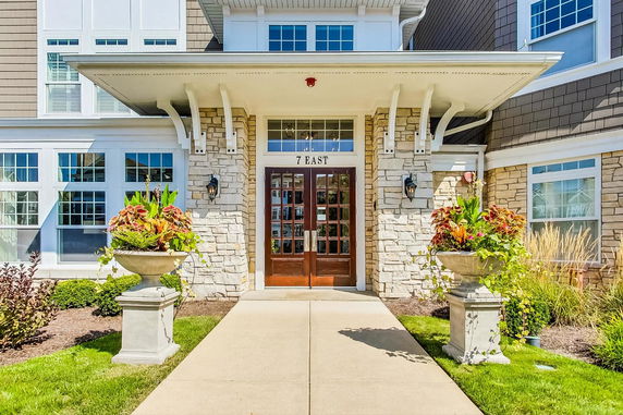 Front view of a building entrance with stone facade and multiple windows.