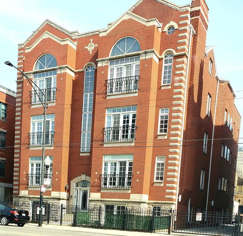 Front view of a multi-story brick building with multiple windows and arched designs.