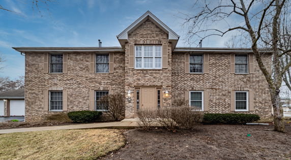 Front view of a two-story brick house with a central entrance and multiple windows.