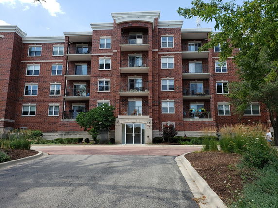 Front view of a multi-story brick apartment building with balconies.