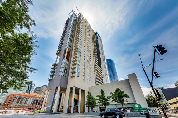 Front view of a tall modern apartment building with numerous balconies.