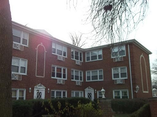 Front view of a three-story brick apartment building with multiple windows.
