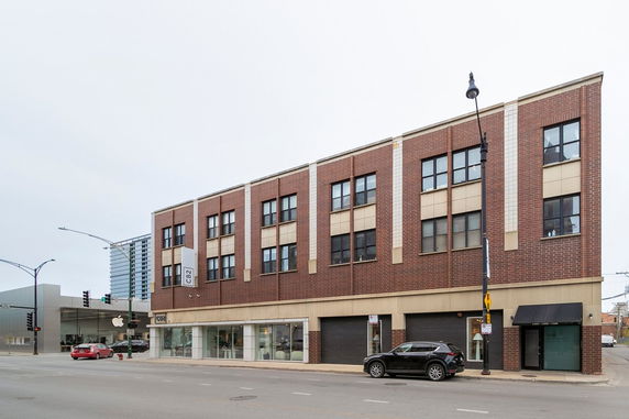 Front view of a multi-story commercial building with brick facade and retail spaces on the ground floor.