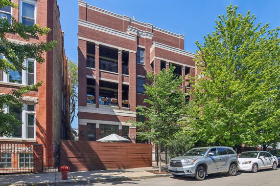Front view of a brick apartment building with balconies.