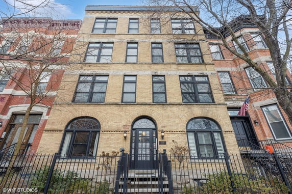 Front view of a multi-story brick building with large windows and an arched entrance.