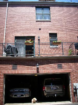Front view of a brick building with a balcony and a double garage.
