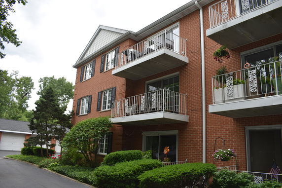 Front view of a multi-story brick building with balconies and a gabled roof.