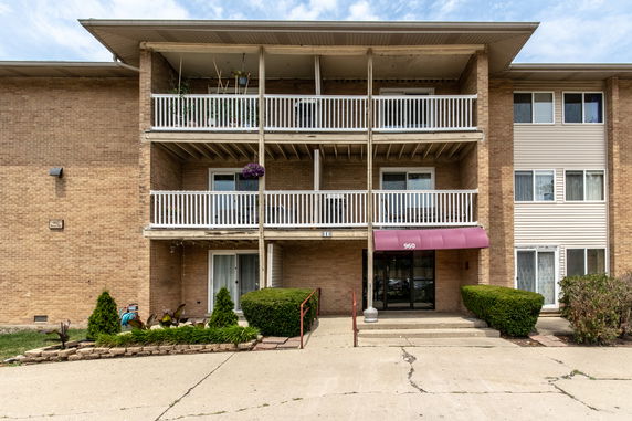 Front view of an apartment building with balconies and an entrance with an awning.
