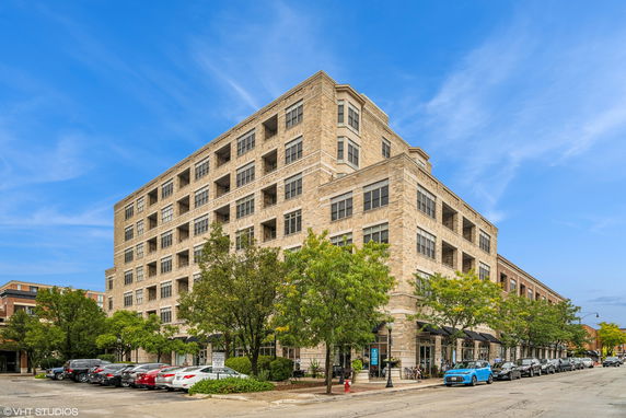 Front view of a multi-story brick building with numerous windows and trees in front.